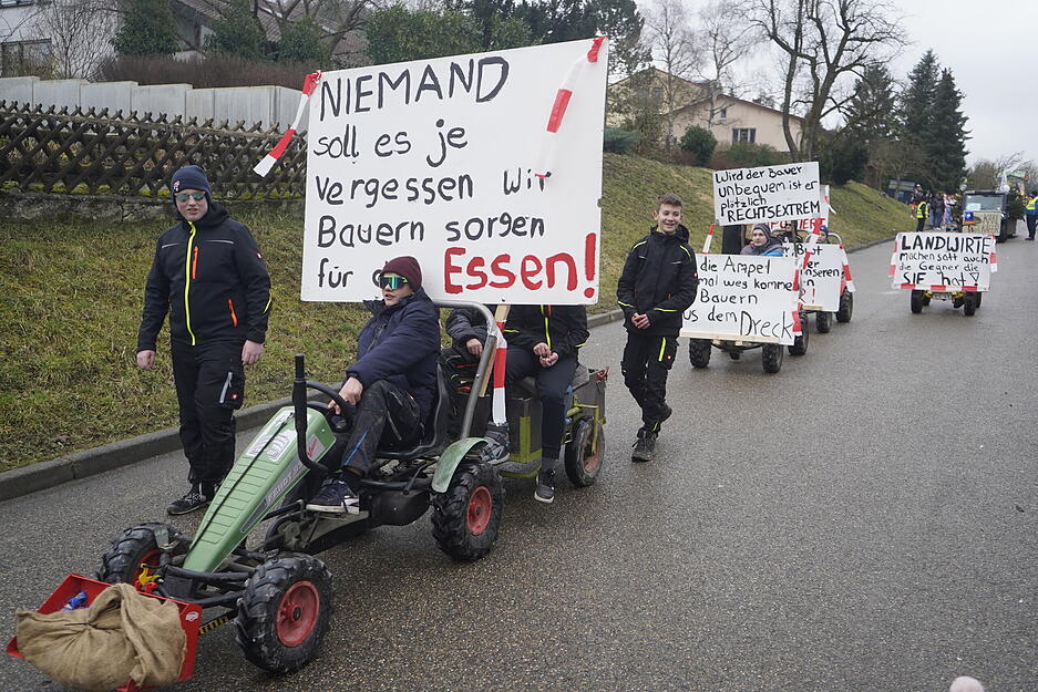 Jugendliche werben auf Tretschleppern für den Erhalt der heimischen Landwirtschaft.