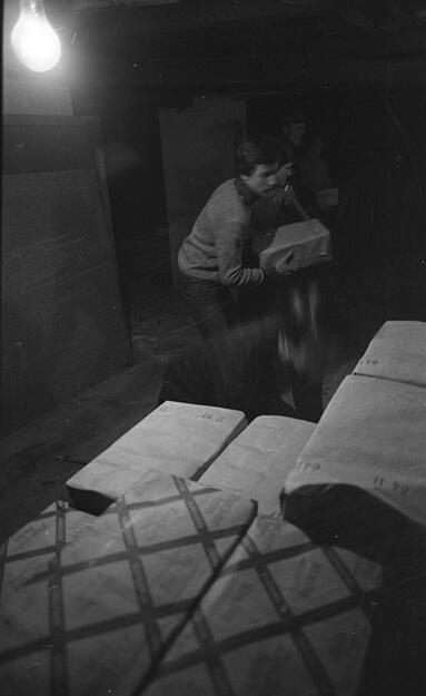 Die Pakete werden sorgsam verstaut. Die Spenden werden in der Garage des Pfarrhauses gestapelt, im Flur des Hauses bahnt man sich einen Weg zwischen unz&auml;hligen Paketen. Aufnahme von Dezember 1981.