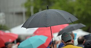 Passanten gehen mit Regenschirmen durch die Stadt. (Symbolbild)