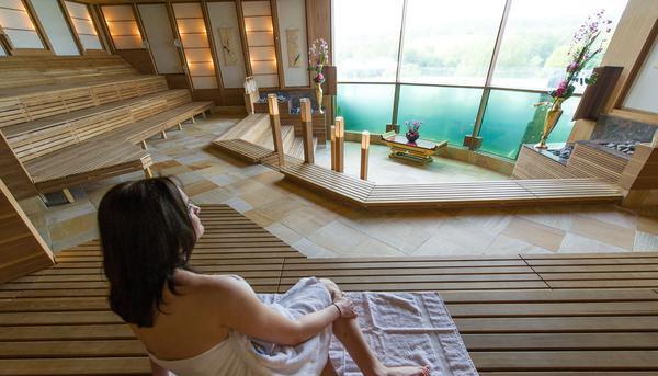 Ein Frau sitzt in der Badewelt Sinsheim in der Koi-Sauna vor der Glaswand eines Aquariums.