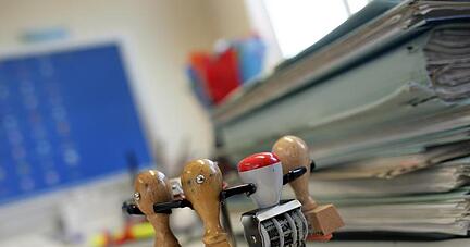 Stempel und Akten auf einem Schreibtisch. Die Industrie fordert die Lockerung von Fristvorgaben und Informationspflichten f&uuml;r Unternehmen.