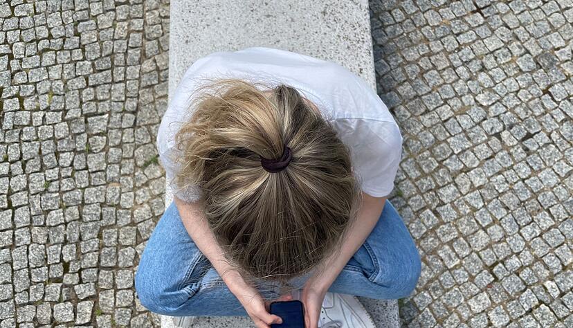 Typische Haltung in heutiger Zeit: mit gesenktem Kopf auf das Handy schauen.