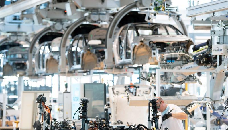 Ein Mitarbeiter arbeitet an der Karosserie eines E-Autos. Die Verdopplung der Rohstoffkosten und fehlende Elektronikchips bremsen derzeit die Autoindustrie aus.