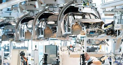 Ein Mitarbeiter arbeitet an der Karosserie eines E-Autos. Die Verdopplung der Rohstoffkosten und fehlende Elektronikchips bremsen derzeit die Autoindustrie aus.