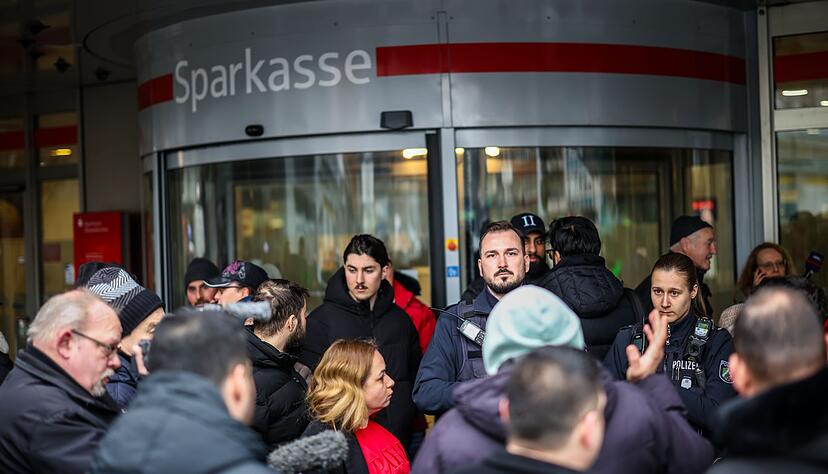 Polizeibeamte sprechen mit m&ouml;glicherweise betroffenen Kunden der Sparkassenfiliale in Buer.