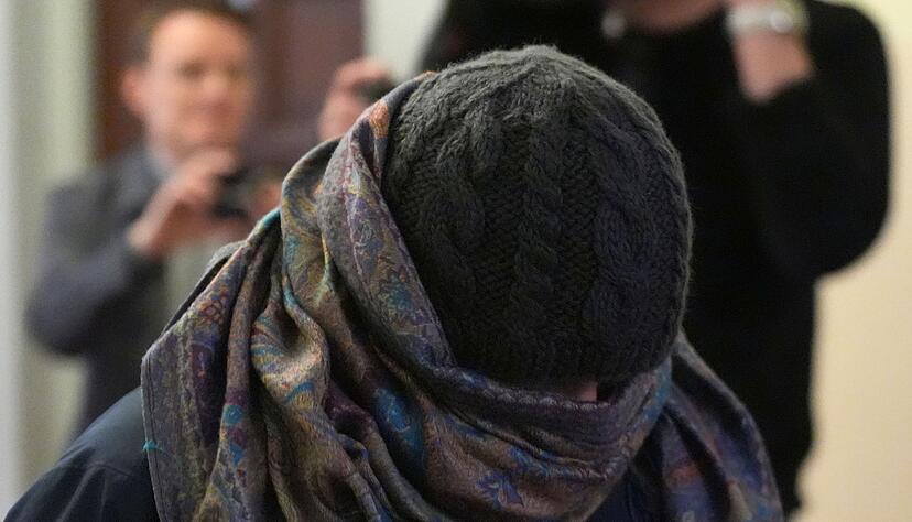 Eine Zeugin verl&auml;sst vermummt den Gerichtssaal.