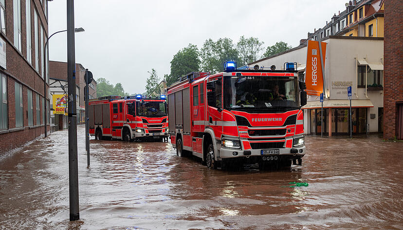 Feuerwehrleute bewegen sich und ihre LKW durch das Hochwasser.