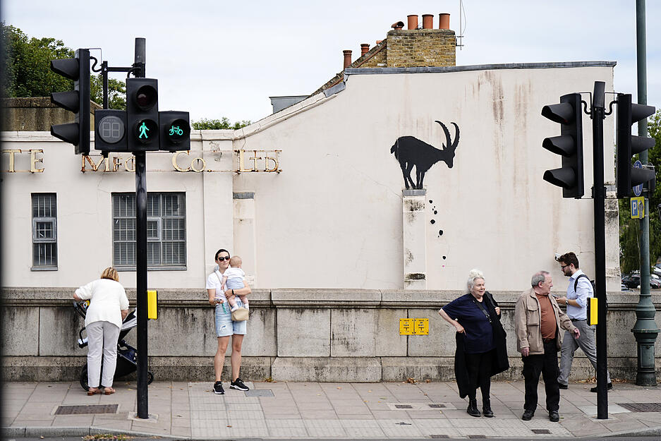 Menschen stehen vor einem neuen Kunstwerk von Banksy, das die Silhouette eines Steinbocks an einer Hauswand in der N&auml;he der Kew Bridge im Westen Londons zeigt.