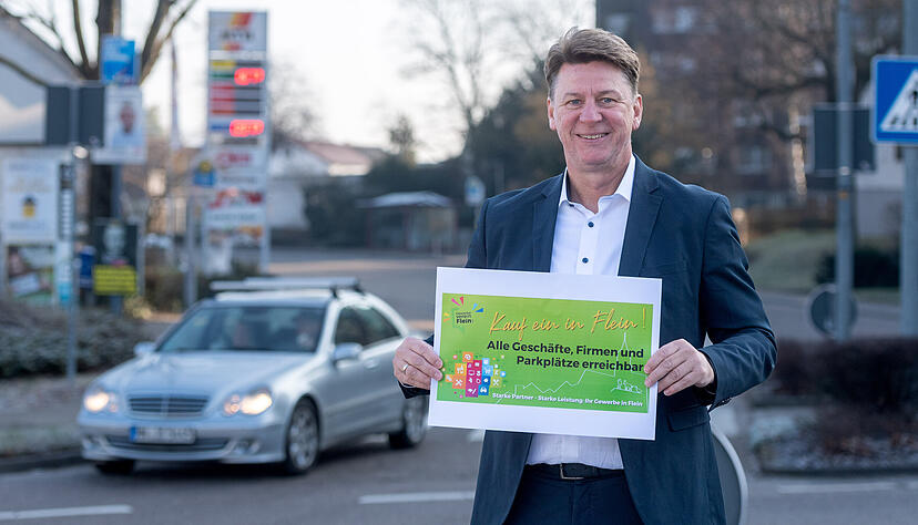 Thomas Schrader zeigt am Kreisel in der Talheimer Stra&szlig;e, dem Startpunkt der Sanierungsarbeiten, den Entwurf f&uuml;r die Werbekampagne w&auml;hrend der Bauphase. Gro&szlig;formatig soll der Kauf-ein-in-Flein-Slogan an den Ortseing&auml;ngen und den &uuml;ber&ouml;rtlichen Umleitungen Kunden weiterhin anziehen.