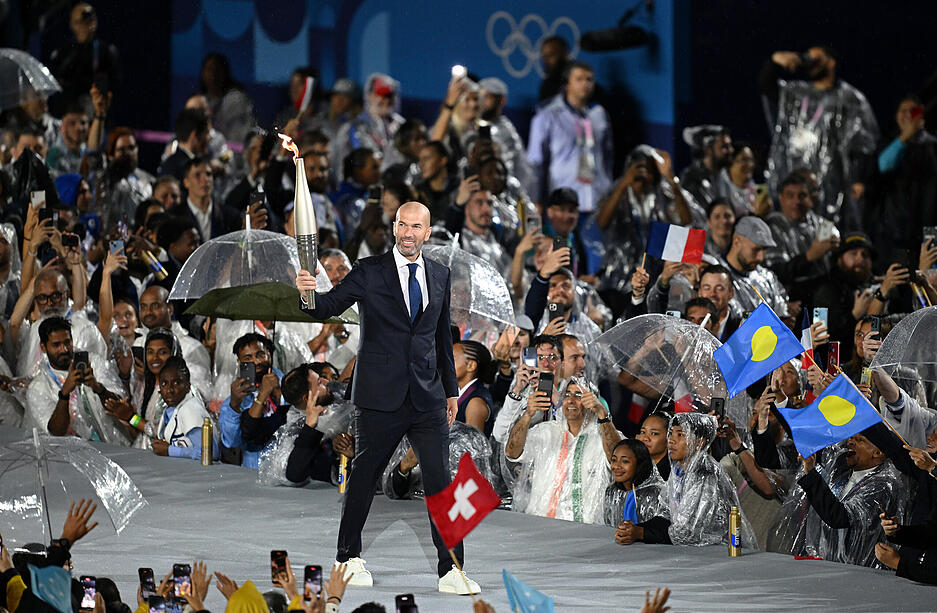 Fußball-Idol Zinedine Zidane trägt die Olympische Fackel.