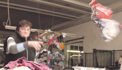 Eine Mitarbeiterin verteilt die Altkleider nach Qualität und Material. Eine Mitarbeiterin verteilt die Altkleider nach Qualität und Material.