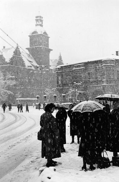 1953: Warm angezogene Frauen warten am Heilbronner Hauptbahnhof auf den Bus. Im Hintergrund ist das Postamt No. 2 zu sehen.