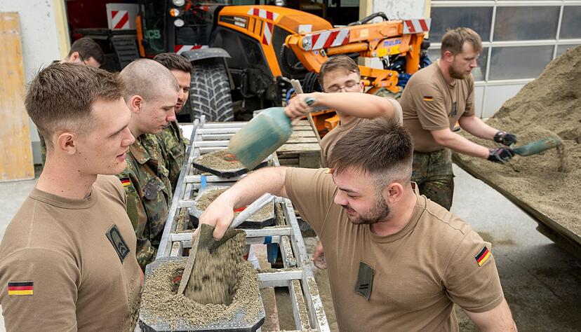 In einem Betonwerk füllen Soldaten der Bundeswehr Sandsäcke ab.