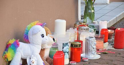 Plüschtiere und Kerzen stehen am Hauseingang zum Tatort in einer Wohnung. Plüschtiere und Kerzen stehen am Hauseingang zum Tatort in einer Wohnung.