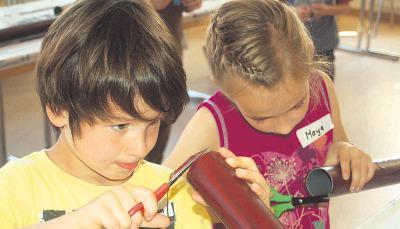 Konzentriert schneidet Jonathan (7) die &uuml;bersch&uuml;ssige Folie von seinem Didgeridoo. Jetzt fehlt nur noch das Mundst&uuml;ck aus Bienenwachs.Foto: Stefanie Pf&auml;ffle