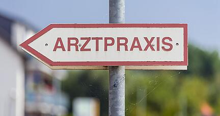 Ein Schild «Arztpraxis» steht an der Straße.