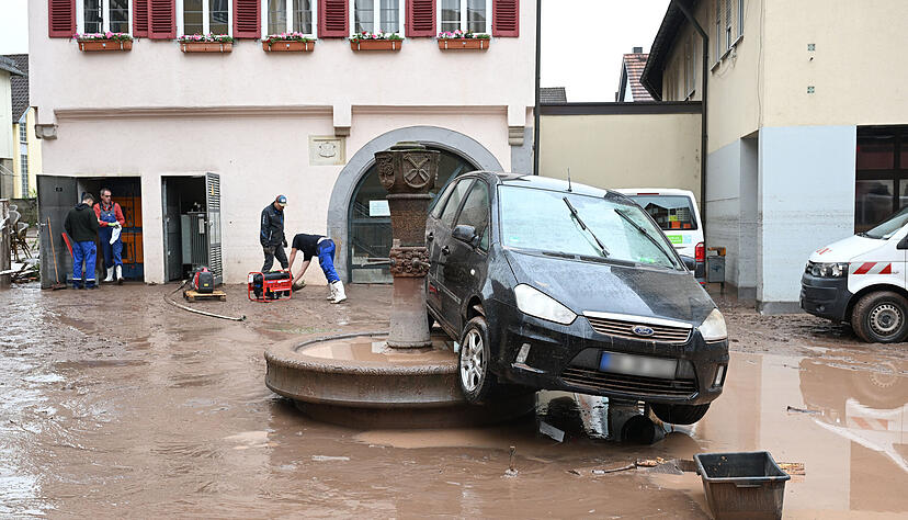 Auf einem Brunnen in Rudersberg steht ein durch ein Hochwasser weggespültes Auto.