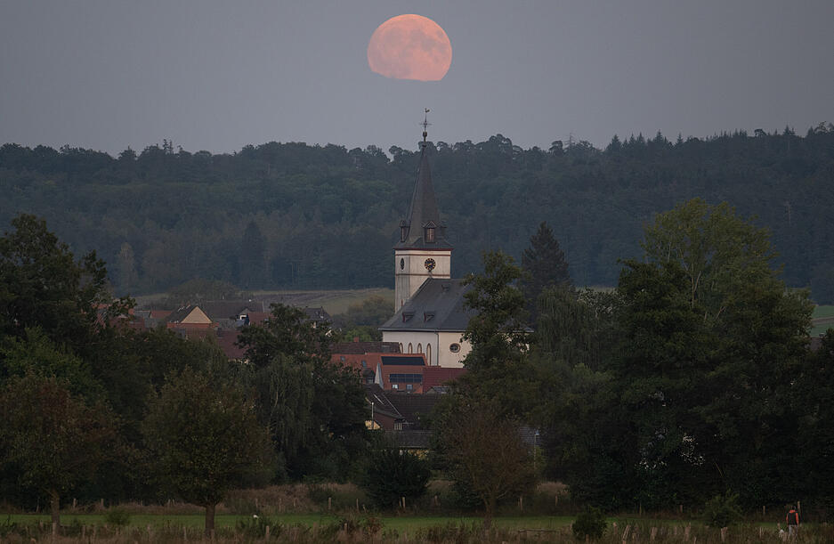 Der "Supermond" geht hinter der Kirche von Wehrheim im hessischen Taunus auf. Durch seine relativ große Nähe zur Erde wirkt der Mond dabei besonders groß.