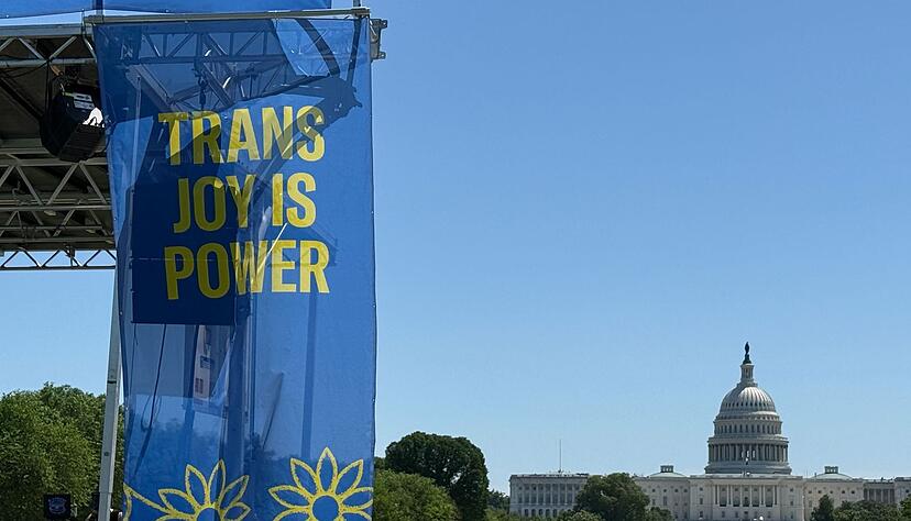&bdquo;Trans joy is power&ldquo; steht auf einem Banner an einer B&uuml;hne vor dem Kapitol am ersten Tag der Worldpride.