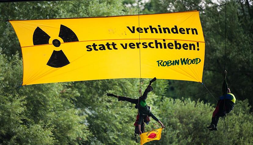 Atomkraftgegner der Umweltschutzorganisation "Robin Wood" seilen sich in Bad Wimpfen von einer Brücke über dem Neckar ab und enthüllen ein Transparent mit der Aufschrift "Verhindern statt verschieben". Die Aktivisten stoppten mit der Aktion zwischenzeitlich den Transport mit hoch radioaktivem Atommüll. Foto: Christoph Schmidt/dpa