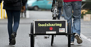 Andreas Kramer zieht am 03.12.2014 in Konstanz am Bodensee (Baden-Württemberg) einen Fahrradanhänger mit der Aufschrift «Foodsharing» über den Markt. Die Initiative Foodsharing sammelt in Konstanz und anderen Städten Lebensmittel ein, die andere in die Mülltonne schmeißen, und verteilt sie weiter. Das kostenlose Essen ist heiß begehrt. Foto: Patrick Seeger/dpa (zu lsw Korr: «Foodsharing will Lebensmittel vor der Mülltonne «retten»» 13.12.2014) ++ +++ dpa-Bildfunk +++