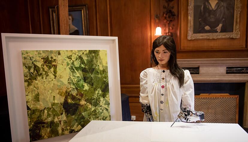 Ai-Da, die weltweit erste Roboterkünstlerin, steht während ihrer Vorstellung auf einer Pressekonferenz am Lady Margaret Hall College der Oxford University neben einem eigenen Kunstwerk.