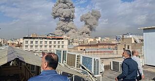 Menschen beobachten Rauch nach einer Explosion in Teheran. (zu dpa: &laquo;Panik in Teheran: Massen fl&uuml;chten aus der Stadt&raquo;)