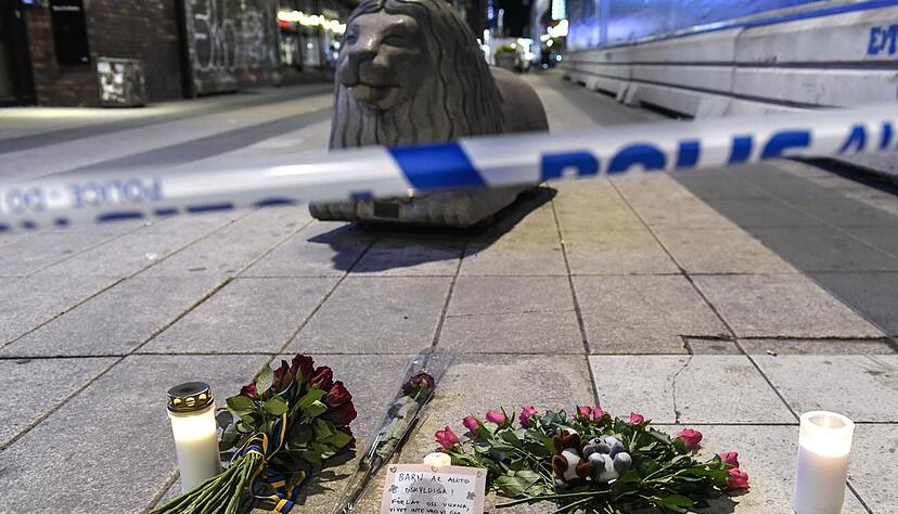 Blumen und Kerzen liegen an einer Polizeiabsperrung in Stockholm. Die Stadt scheint still zu stehen. Foto: dpa