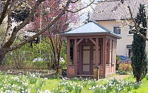 Natur und Historie vereint: ein Gartenhaus aus Backsteinen und Holzelementen inmitten blühender Flächen. Hinten links blüht eine Blutpflaume. Natur und Historie vereint: ein Gartenhaus aus Backsteinen und Holzelementen inmitten blühender Flächen. Hinten links blüht eine Blutpflaume.