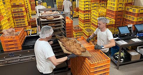 Beim Verteilen der Backwaren in die gelben Kisten herrscht Hochbetrieb. Dejan (l.) und Adrian verladen gerade frisch gebackene Focaccia. Beim Verteilen der Backwaren in die gelben Kisten herrscht Hochbetrieb. Dejan (l.) und Adrian verladen gerade frisch gebackene Focaccia.