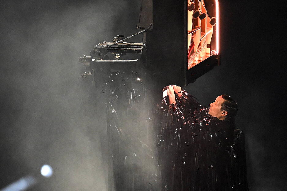 Ein Pianist hing vertikal in der Luft und spielte mit dem Rücken zum Boden.