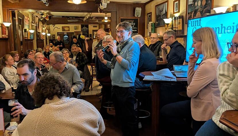 Bj&ouml;rn Schwarz (mitte, am Mikrofon) spricht im Ph&ouml;nix Irish Pub zu den anwesenden 5ive-G&auml;sten.