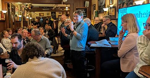 Bj&ouml;rn Schwarz (mitte, am Mikrofon) spricht im Ph&ouml;nix Irish Pub zu den anwesenden 5ive-G&auml;sten.