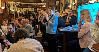 Bj&ouml;rn Schwarz (mitte, am Mikrofon) spricht im Ph&ouml;nix Irish Pub zu den anwesenden 5ive-G&auml;sten.