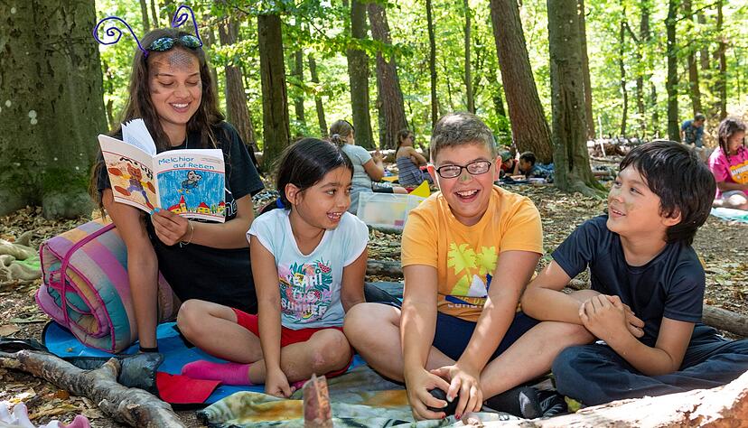Jede Menge Gekicher: Mariam, Lion und Juki haben sichtlich Spa&szlig;, als Tabea Singh, heute als Schnecke unterwegs, ihnen vorliest.