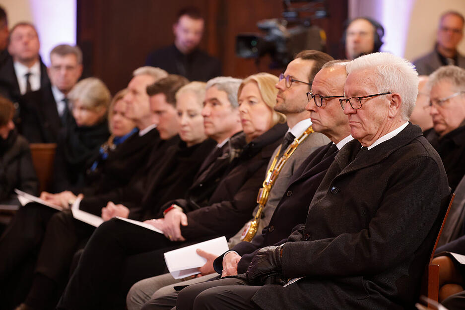 Die Trauergäste, darunter Winfried Kretschmann (Bündnis 90/Die Grünen, r), Ministerpräsident von Baden-Württemberg, und Friedrich Merz (2.v.r.), Bundesvorsitzender der CDU, sitzen beim Gottesdienst bei der Trauerfeier für Wolfgang Schäuble in der Kirche.