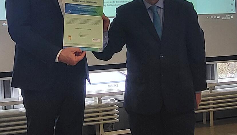 Dieter Arweiler, Schulleiter der Andreas-Schneider-Schule, bekommt von Dr. Kambiz Ghawami vom World University Service die Zertifizierungsurkunde &uuml;berreicht.