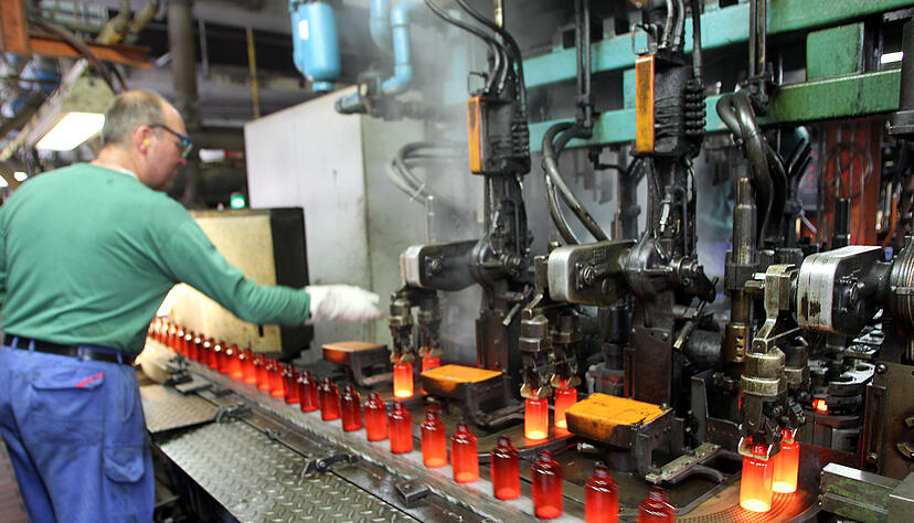 Kleine Glasflaschen werden in einer Glasfabrik mit einer Maschine in Formen gegossen und ausgeblasen. Die energieintensive Glasindustrie hat mit den hohen Strom- und Gaspreisen schwer zu k&auml;mpfen - nun kommen auch noch Sorgen um die Versorgungssicherheit hinzu.