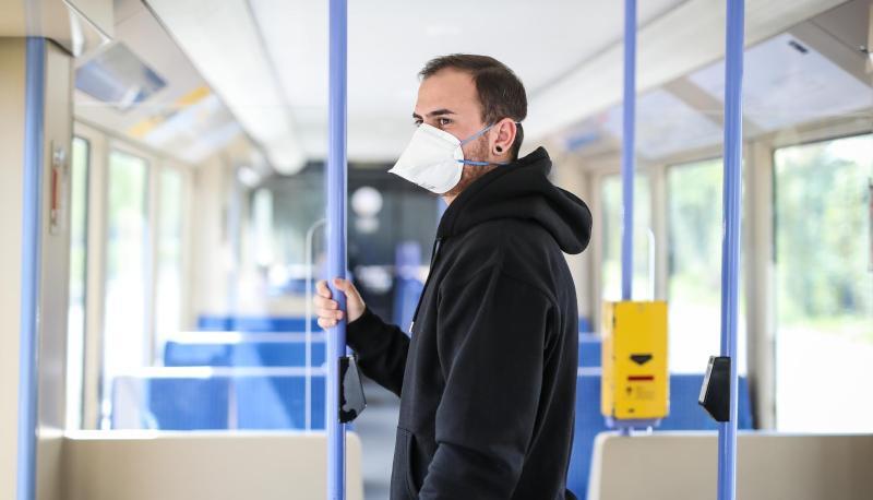 Ein junger Mann trägt in einer Stadtbahn eine Atemschutzmaske.