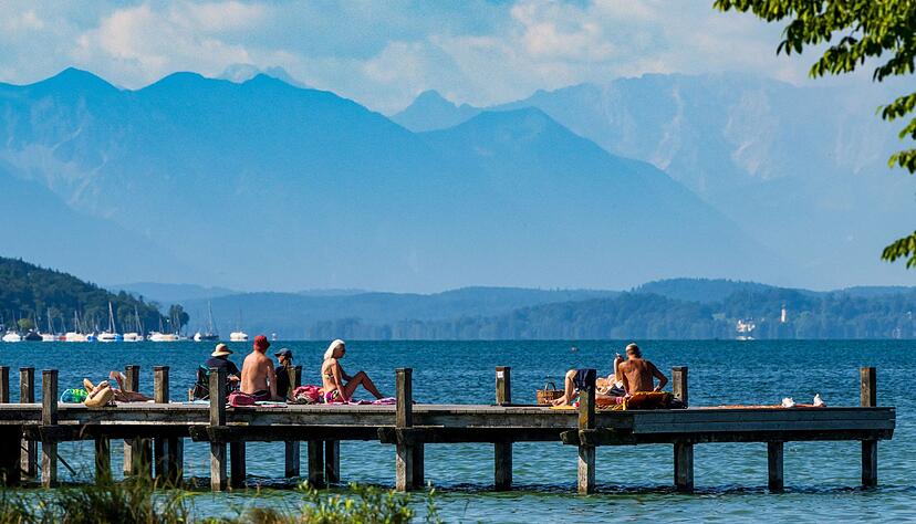 Sonnenhungrige geniessen das warme Wetter auf einem Steg im Starnberger See. Sonnenhungrige geniessen das warme Wetter auf einem Steg im Starnberger See.