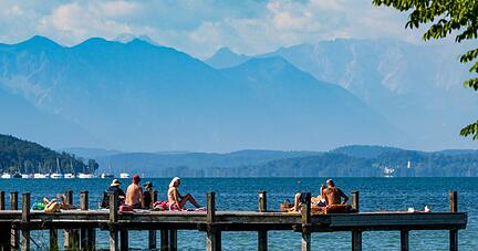 Sonnenhungrige geniessen das warme Wetter auf einem Steg im Starnberger See.