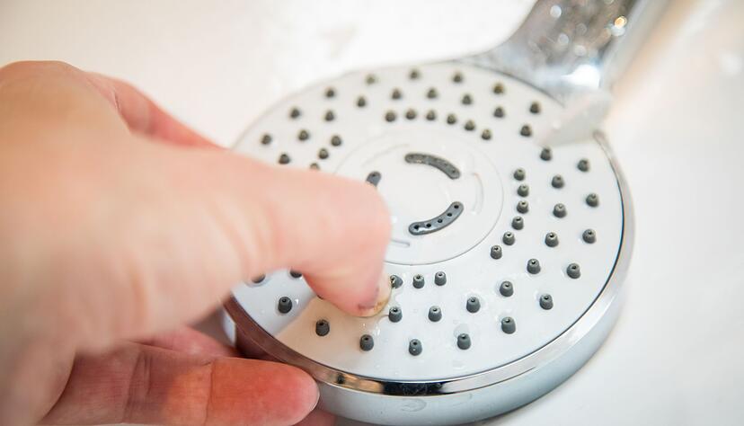 Ausprobiert: Mit dem Finger l&auml;sst sich der Kalk nicht so einfach von den D&uuml;sen des Duschkopfs entfernen.