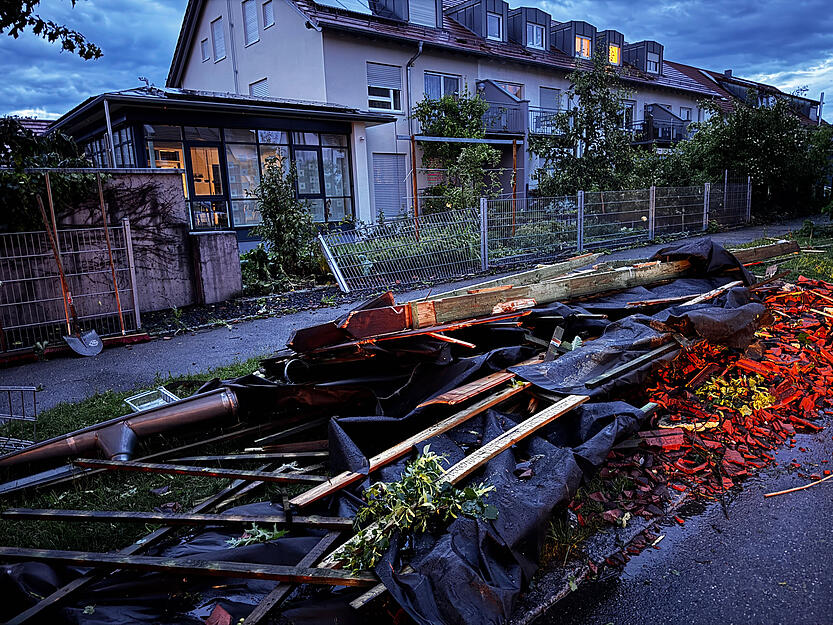 Nach dem Unwetter im Alb-Donau-Kreis liegen Dachrinnen, Holzbalken und kaputte Dachziegel auf einer Straße. Sturmböen, Starkregen und heftige Gewitter waren zuvor über weite Teile Baden-Württembergs hinweggezogen. Nach dem Unwetter im Alb-Donau-Kreis liegen Dachrinnen, Holzbalken und kaputte Dachziegel auf einer Straße. Sturmböen, Starkregen und heftige Gewitter waren zuvor über weite Teile Baden-Württembergs hinweggezogen.