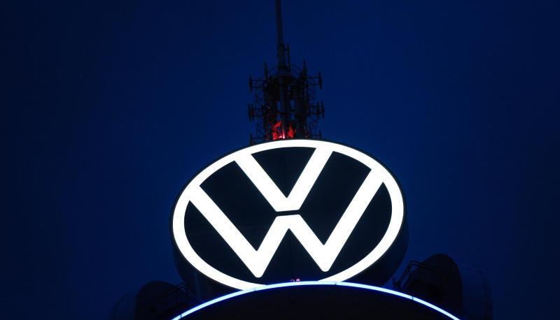 Das Volkswagen Logo leuchtet auf dem VW-Tower vor dunklem Himmel.