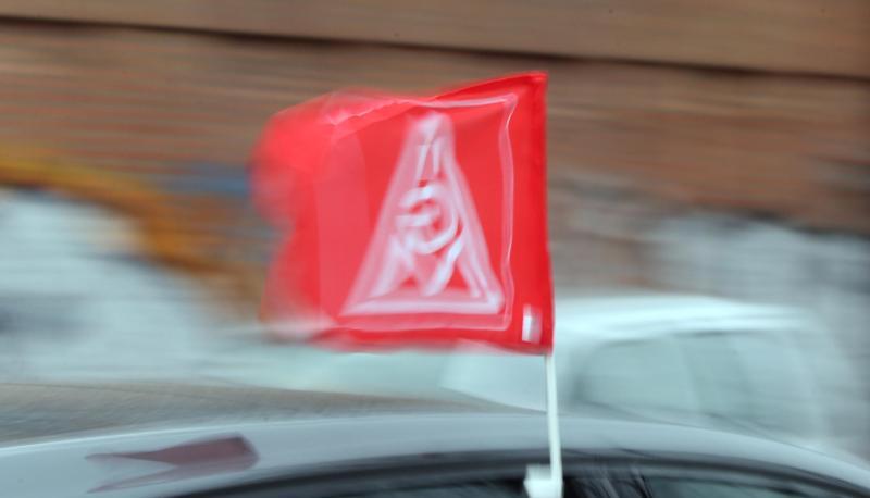 Eine Fahne mit dem Logo der IG Metall an einem Auto.