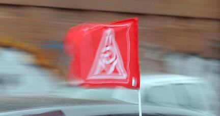 Eine Fahne mit dem Logo der IG Metall an einem Auto.