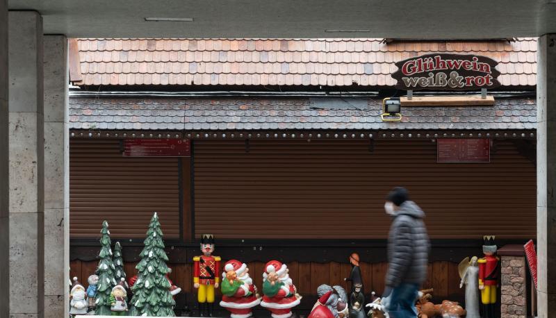Ein Mann geht an einer Weihnachtsmarktsbude vorbei.