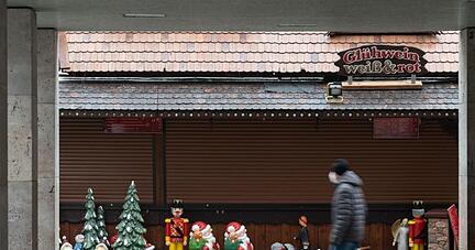 Ein Mann geht an einer Weihnachtsmarktsbude vorbei.