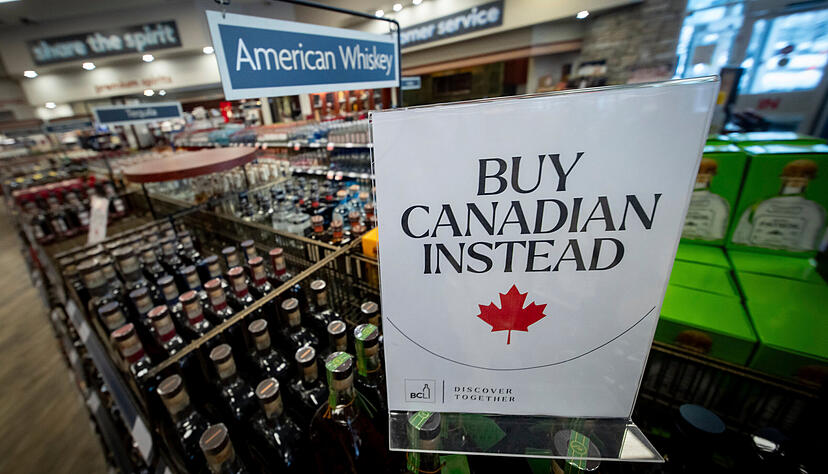 Kanada hat bereits reagiert: Ein Schild ruft vor einem Regal mit amerikanischem Whiskey in einem Spirituosengeschäft zum Kauf kanadischer Produkte auf.