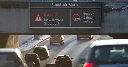 Autos fahren am Montag in Stuttgart durch die Innenstadt, während auf einer Anzeige ein Feinstaub-Alarm für die Umweltzone Stuttgart angezeigt und auf öffentliche Verkehrsmittel hingewiesen wird. Foto: dpa